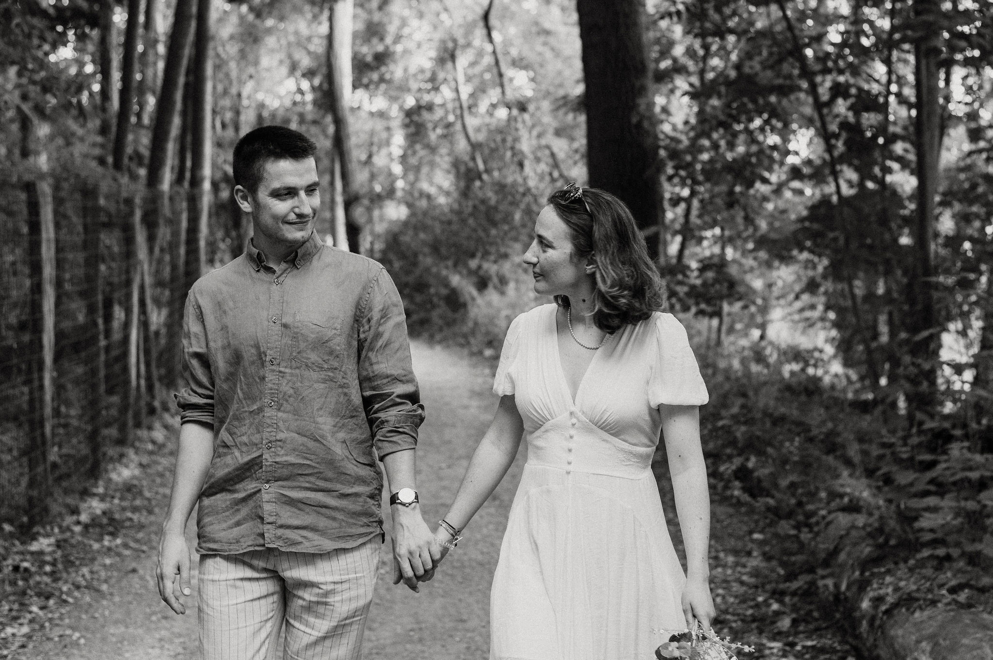 Photo noir et blanc d'un couple souriant se promenant en forêt, séance photo de couple