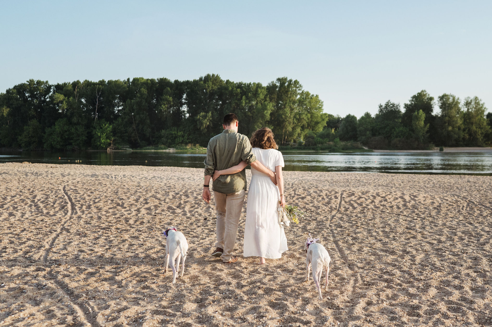 Couple se promenant main dans la main le long d'un plan d'eau bordé d'arbres, près d'Orléans