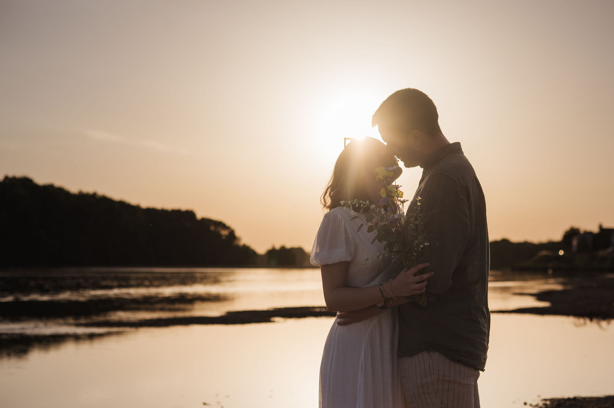 Silhouette d'un couple s'embrassant devant un coucher de soleil spectaculaire à Combleux