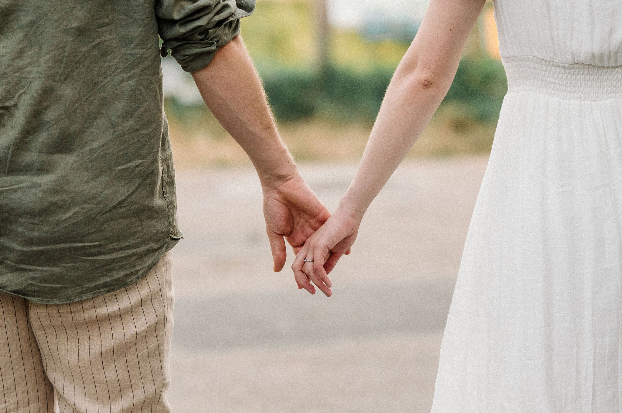 Gros plan sur les mains entrelacées d'un couple, détail tendre d'une séance photo naturelle