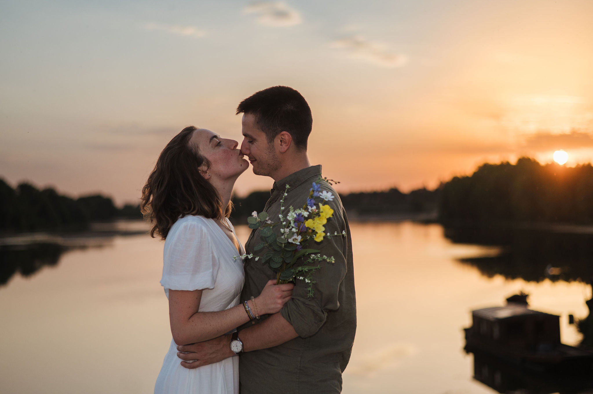 Couple s'embrassant tendrement au coucher du soleil au bord de l'eau à Combleux