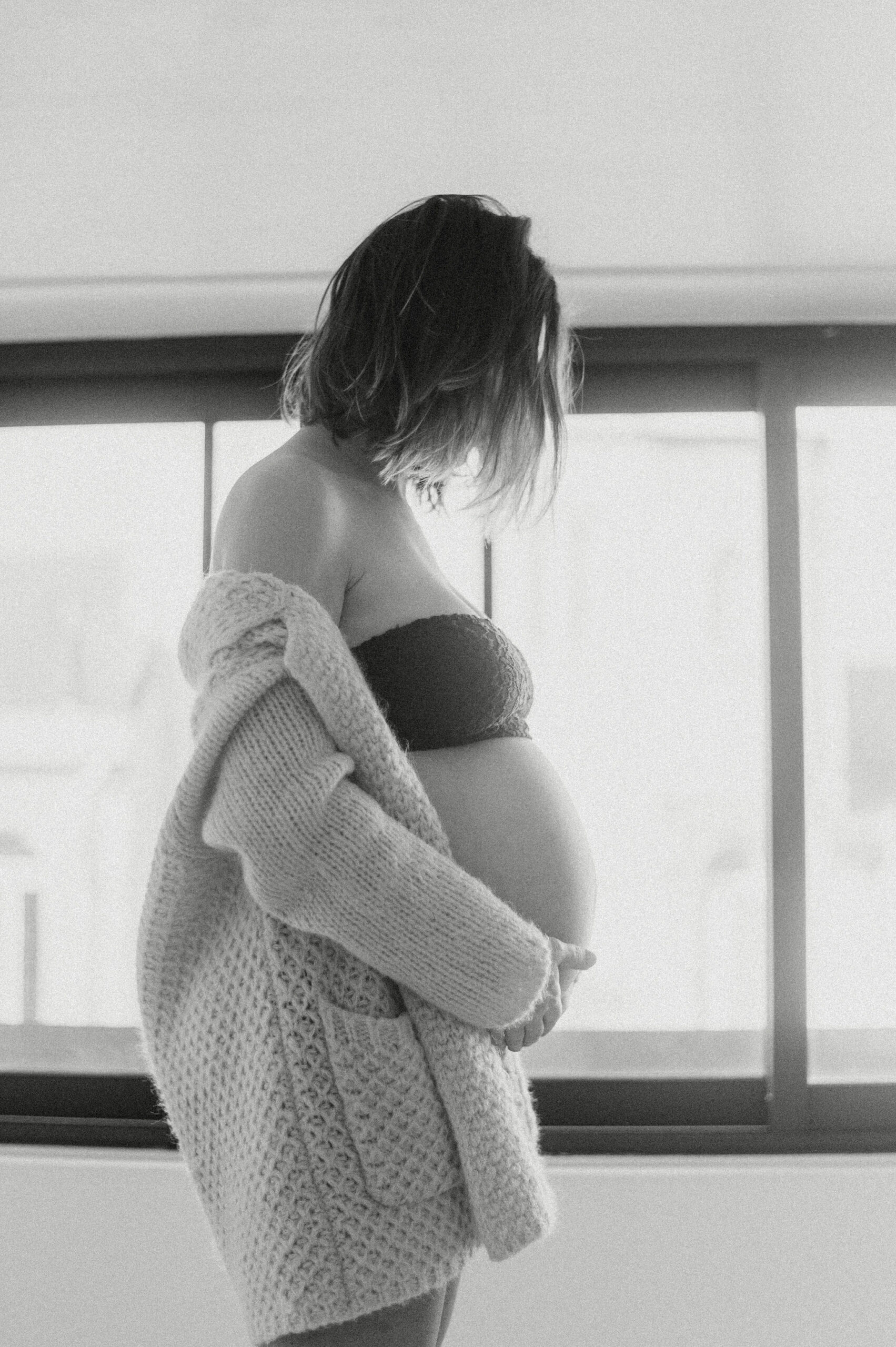 Silhouette de future maman près d'une fenêtre, photo noir et blanc