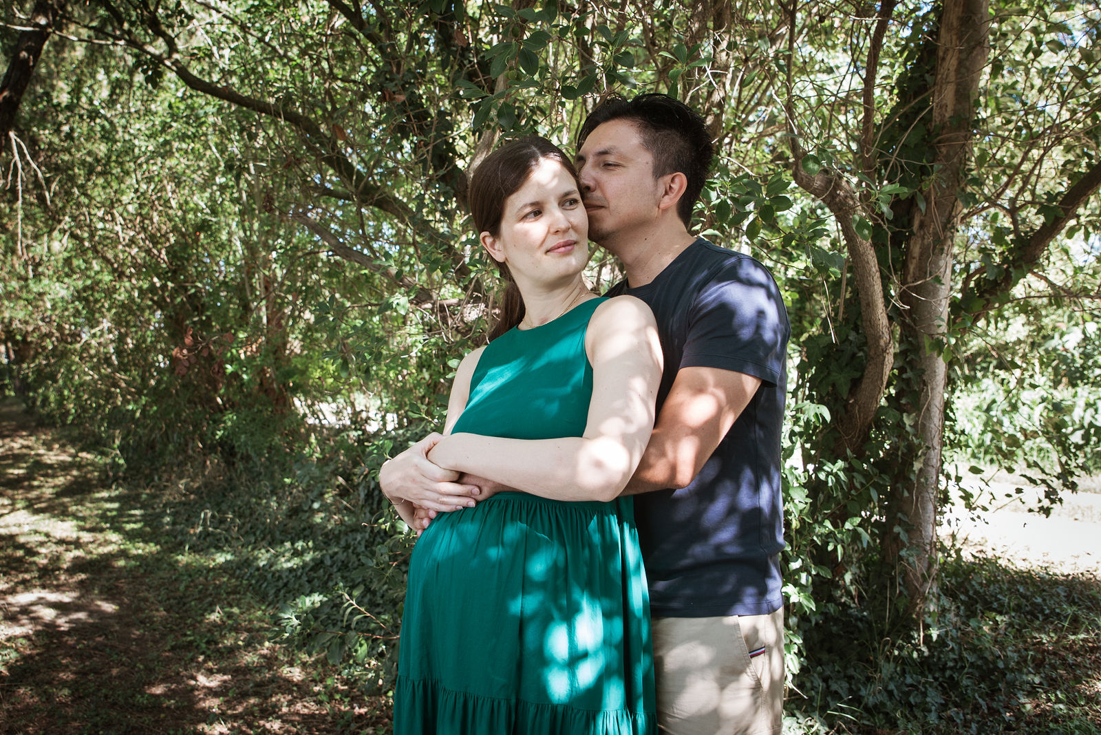 Futurs parents enlacés sous les arbres, séance grossesse en extérieur